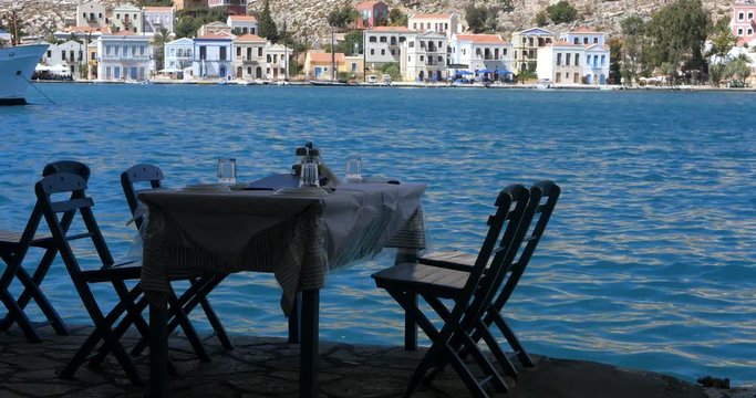 wooden table and chairs prepared for clients by the sea coast of Kastellorizo, Greece. Beautiful background.