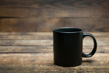 A black cup stands on a wooden table. Tea and coffee in the morning.