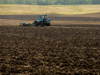 Tractors plow plowland on an autumn clear day