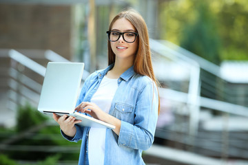 Young woman holding laptop computer on the street