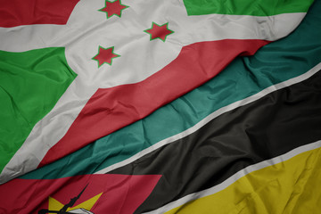 Obraz premium waving colorful flag of mozambique and national flag of burundi .