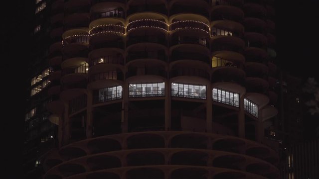 NX typical generic luxury round apartment building exterior establishing shot at night. Lights in windows brighten rooms inside fancy condo