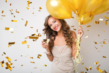 attractive young stylish woman celebrating new year, drinking champagne holding air balloons,...