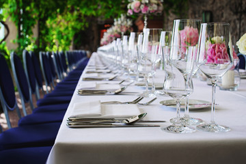 many drinking glasses stand in a row on the decorated table in the restaurant