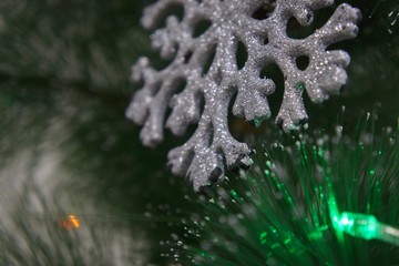 Decorative silver  snowflake toy on Christmas green tree. Approach of new year 2020. Front view is close. Soft selective focus.