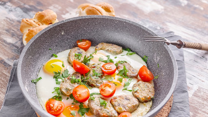 Close up fried eggs with vegetable nuggets in a gray ceramic frying pan. Tasty breakfast