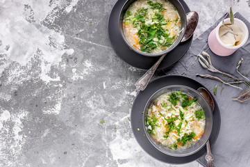 Chicken noodle soup with herbs and cheese sauce on a gray concrete background. Horizontal shot. Top view. Copy space