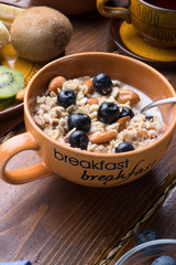 bowl of oatmeal porridge with blueberries, fruits,  almonds and coconut milk. Healthy and tasty vegan breakfast. close up