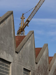 Industrial archeology buildings in the city of Busto Arsizio. Facade of ancient factory shed. Construction crane.