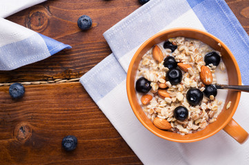 bowl of oatmeal porridge with blueberries, fruits,  almonds and coconut milk. Healthy and tasty vegan breakfast. top view, flat lay.