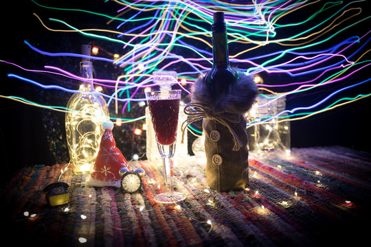 Red wine in crystal glass with bottle on colorful carpet with creative New Year artwork decorations. Copy space