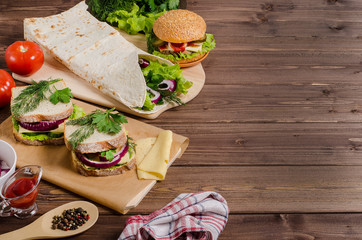 Hamburger, shawarma, sandwiches on a dark wooden background with copy space. Fast food recipes.