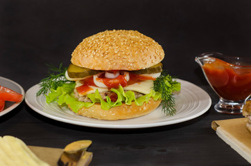 Ready-made hamburger with ingredients on a plate on a black wooden background. For advertising, menu.
