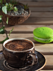 Brown cup with espresso and almond cookies. Close-up. Coffee time. Еcheveria succulent - indoor plants in a coconut pot, on a wooden table in the background. Vertical orientation.