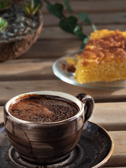 Brown cup with espresso and homemade lemon pie. Close-up. Coffee time. Еcheveria succulent - indoor plants in a coconut pot, on a wooden table in the background. Vertical orientation.