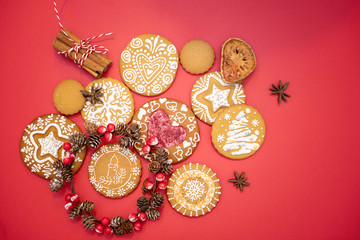 Christmas gingerbread covered with a pattern of white glaze with a Christmas wreath, cinnamon sticks on a red background.