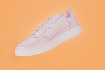fashion sneakers on a beige background. hanging on shoelaces