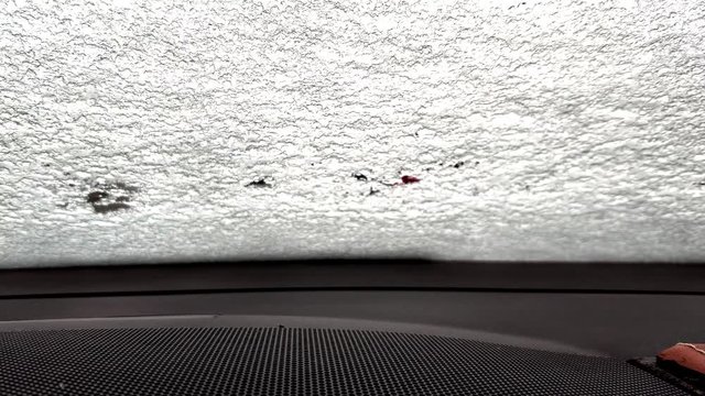 snow melts quickly on the windshield of the car, view from the inside of the car. Time lapse from frozen glass to fully thawed. Heated glass and webasto heats the interior