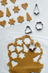 The process of making gingerbread cookies with rolling pin and sprinkled flour on a light gray background. Vertical orientation