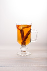 One glass glass of apple tea with cinnamon on a light background.