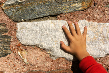little boy is touching stone wall with his hand