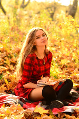 Obraz na płótnie Canvas Outdoor fashion photo of young beautiful lady surrounded autumn leaves