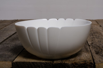 Top view of blank white dish and white tablecloth on a wood background with copy space