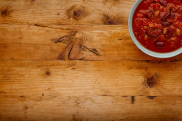A bowl of delicious chilli bean soup,, in a rustic bowl, on a wooden background with copy space.