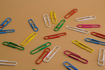 heap of multicolored paperclips scattered on a brown background