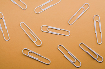 pile of white paper clips spread out at a distance from each other against a brown background