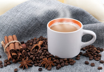 cup of milk coffee on colored cloth and roasted coffee beans close up