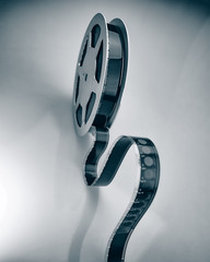 Aluminum reel with 16mm film on a colored background, close-up.