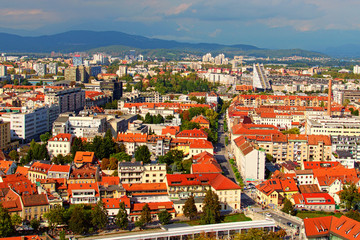 Fototapeta na wymiar Ljubljana, Slovenia-September 29, 2019:Picturesque aerial view of old part or the city at sunny autumn day. Ancient buildings with red tile roofs, mountain range in the back ground. Vibrant sky