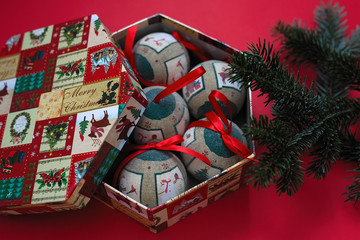 Christmas balls in holiday box on red paper background.