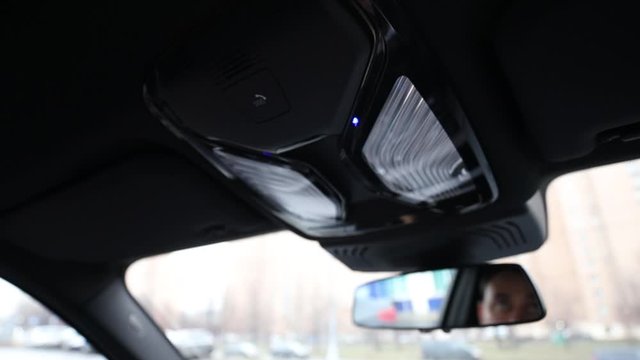 A man, a car driver clicks on the SOS button which is on the ceiling