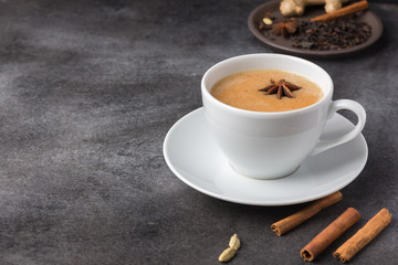 Traditional indian masala tea in a white cup on a dark background, copy space