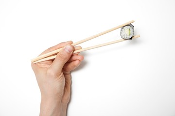 Man's hand holding sushi roll in chopsticks against white background