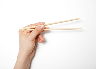 Man's hand gripping chopsticks over white background