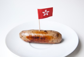 Fried sausage in plate with Hong Kong flag decoration against white background