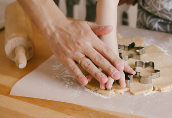Mom and Dad teach a young child how to make cookies in the kitchen. family baking