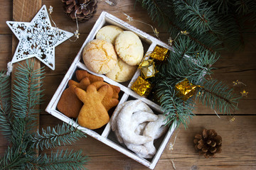Assorted Christmas cookies and Christmas decorations in a wooden box on a wooden background. Rustic style.