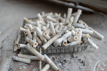 full and dirty crystal ashtray on a gray wooden background