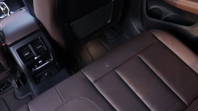 Brown leather interior in a premium SUV. Rear seats, top view of climate control, doors and seats