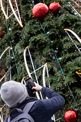 Fototapeta na wymiar A man taking a photo with a phone of a Christmas tree
