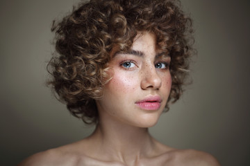 Fototapeta premium Vintage style portrait of young beautiful freckled girl with curly hair and clean makeup, selective focus
