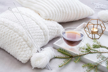 Cozy knitting set with white yarn and knitting needles with tea in the foreground