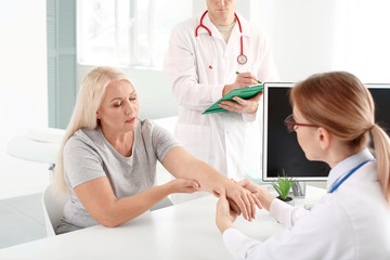 Doctor examining mature woman with joint pain in clinic