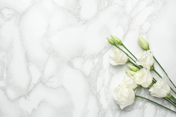 White eustoma flowers on marble background with copyspace. Minimalistic composition for the holidays.