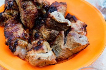 Pieces of grilled pork on plate close up
