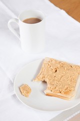 Coffee mug and peanut butter on wheat bread